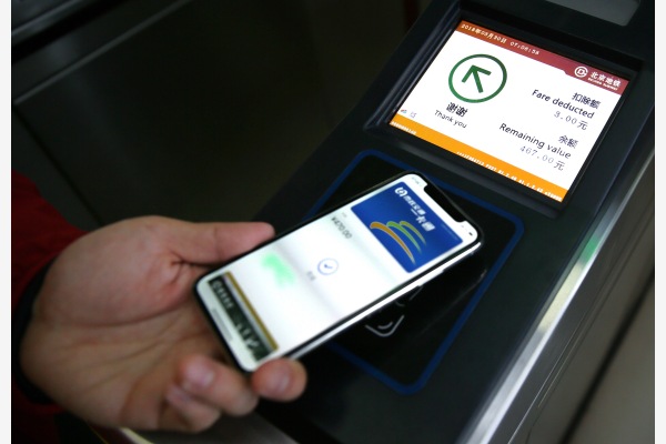 在北京呼家楼地铁,一名苹果公司工作人员展示刷iPhone手机进站。新华社资料图