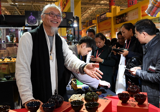 去年11月，台商廖继文（左一）在第十二届海峡两岸茶业博览会上推介茶具。新华社
