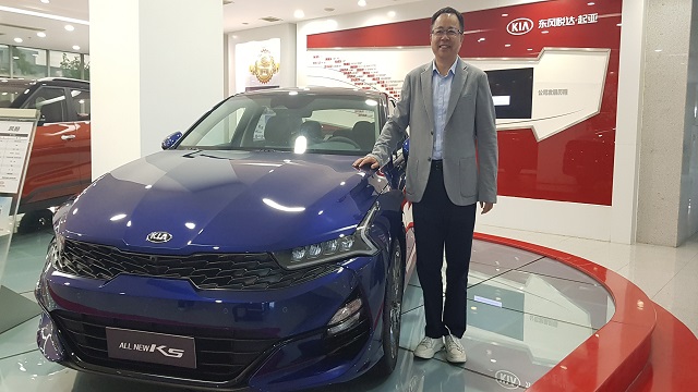 东风悦达起亚总经理李峰在接受采访前，与公司门前的车型合影。（图/第一财经 权小星）