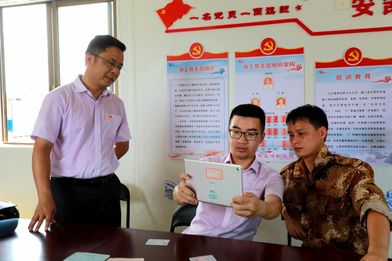 农行连江县丹凤支行党支部书记陈宝（左）带领客户经理到同心村海上党支部为渔民黄安登（右）办理贷款