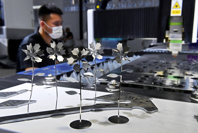 一台激光切割机在第25届青岛国际机床展览会制作金属花朵。