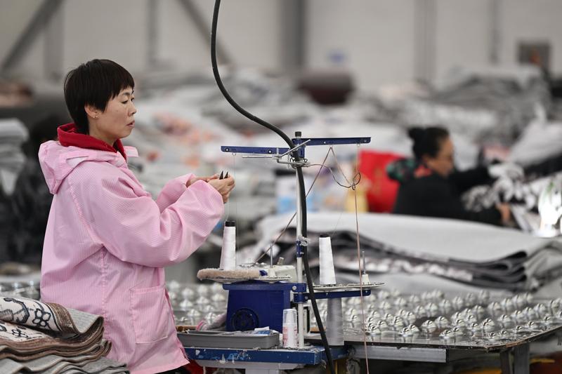 在天津市的一家地毯生产企业，工人在缝纫机上放线。新华社资料图