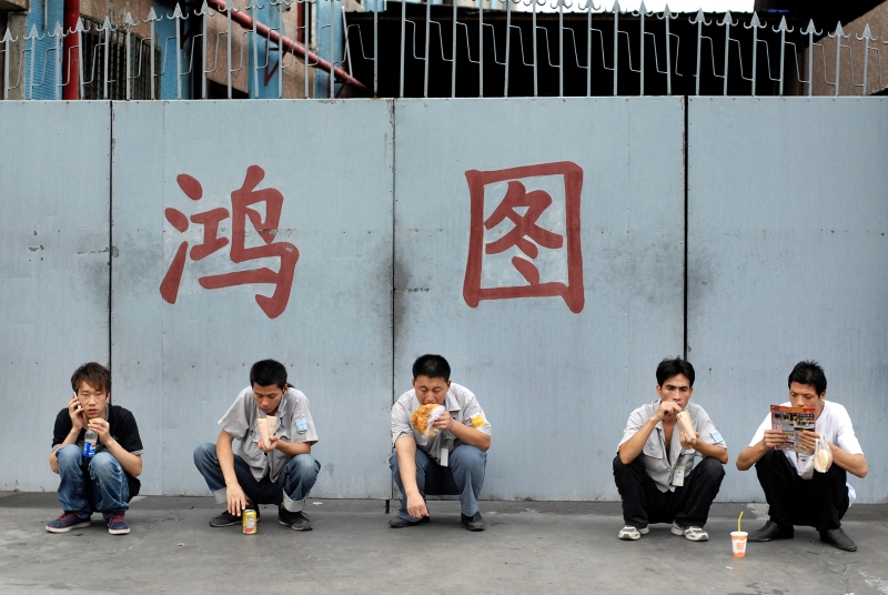 2011年9月4日，广东东莞，一家铸造厂的工人下班后，在厂门前边吃东西边放风。这只是暂时充饥，等到晚上10点钟加完班后，他们回到出租屋再自己做晚饭。
