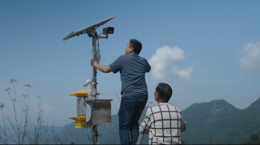 △农场负责人蔡青松和村民一起调整海康威视的设备