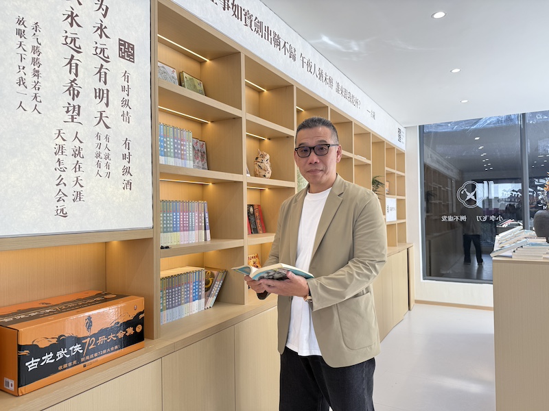 郑小龙翻看着父亲的书，想象着假如父亲来到这里，“应该会想要跟我喝一杯吧。”（吴丹拍摄）