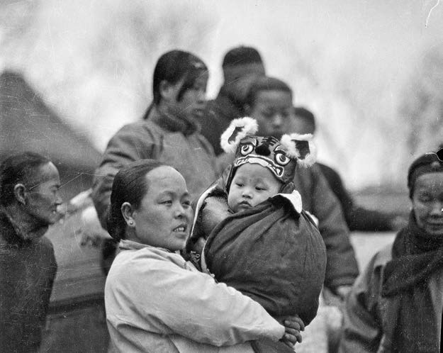 保姆抱着戴虎头帽的婴儿(上海教育出版社供图)