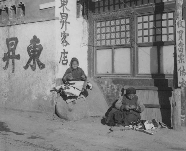 做缝补活儿的妇女在街边的店门口工作(上海教育出版社供图)