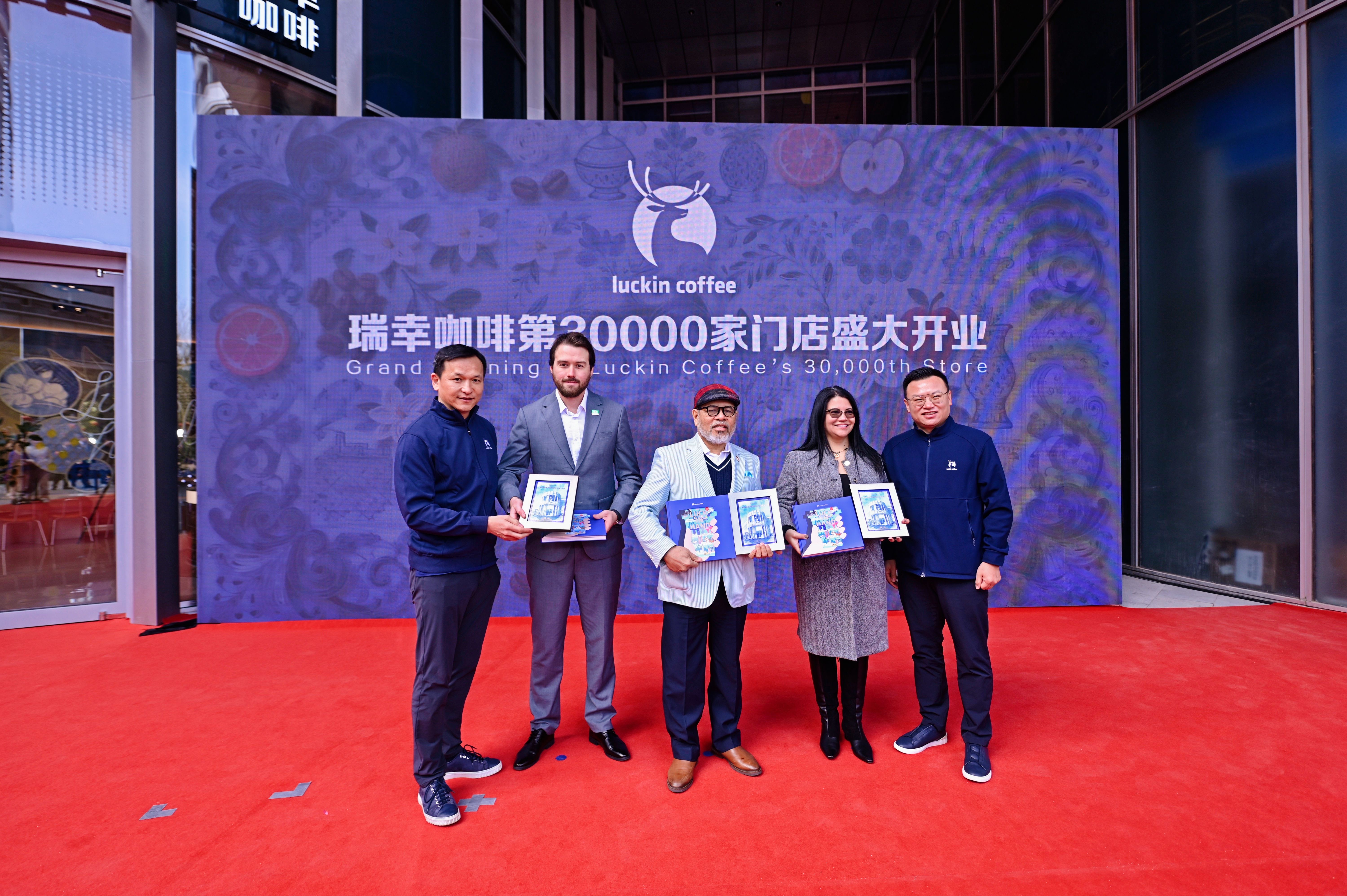 （大钲资本董事长兼首席执行官、瑞幸咖啡董事长黎辉（左一），瑞幸咖啡联合创始人、首席执行官郭谨一（右一）向印度尼西亚共和国驻华大使周浩黎（中）、巴西出口投资促进局亚太区总经理维克多（左二）、哥伦比亚驻广州总领事安雅（右二）赠送纪念礼物）