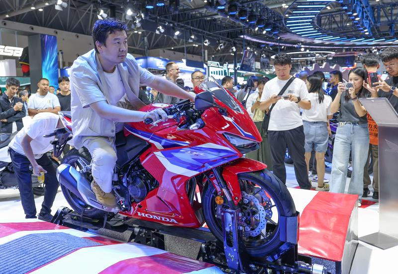 去年9月,观众在重庆摩博会现场体验摩托车模拟驾驶。新华社