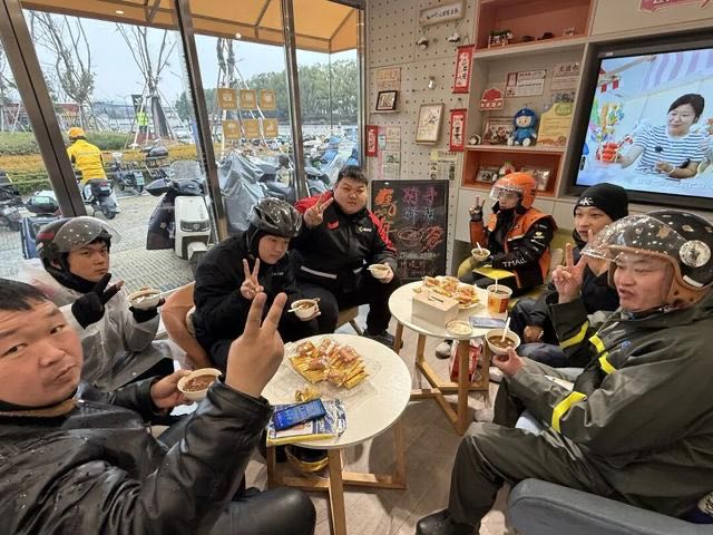 快递员们业务间隙时段在小哥驿站品尝腊八粥