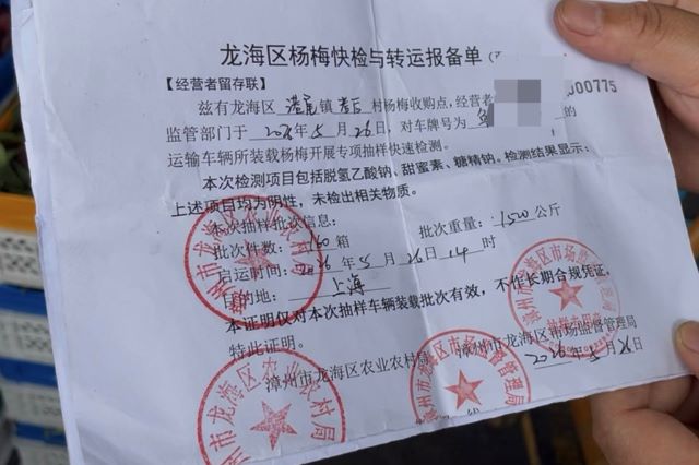 西郊国际内的杨梅批发商展示随车抽检的检测证明。摄影/冯小芯