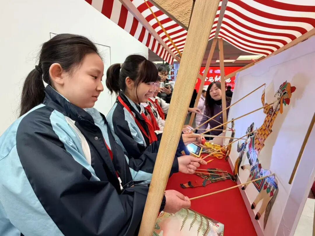 钱梓悦(左一)和康外小记者们一起体验皮影戏节目表演