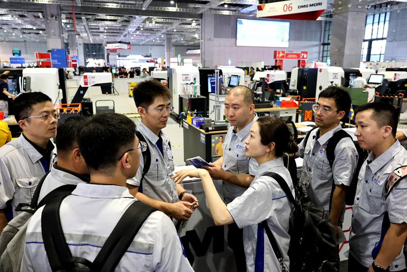 9月24日,来自通用技术集团的产业工人在数控铣赛项现场外交流讨论。
