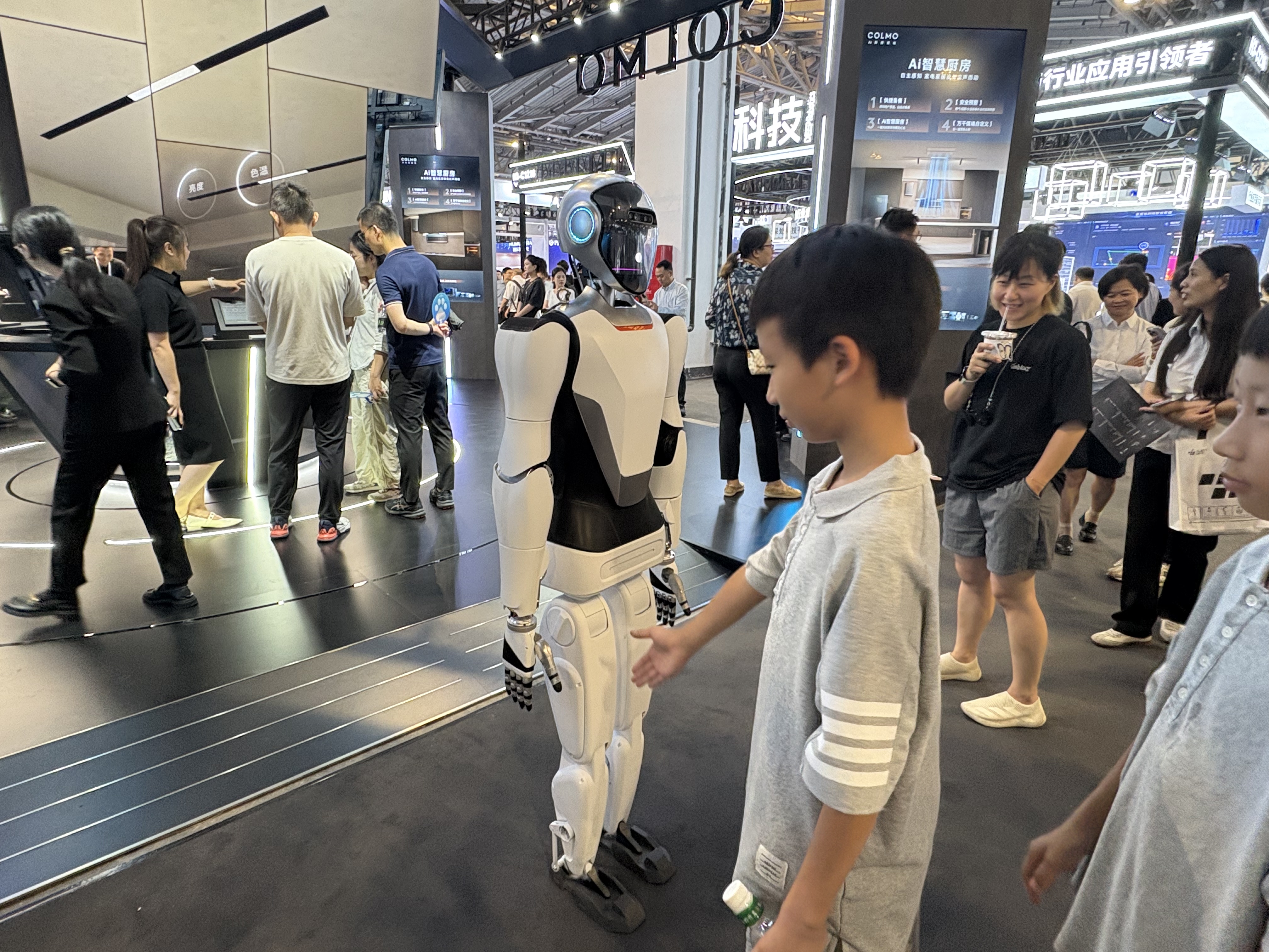 “小孩儿哥”试图跟机器人互动。图片来源：乔心怡
